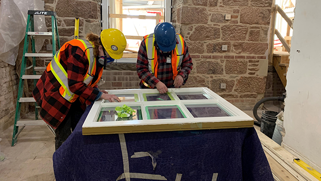 Two students work on repairing an old window at Province House