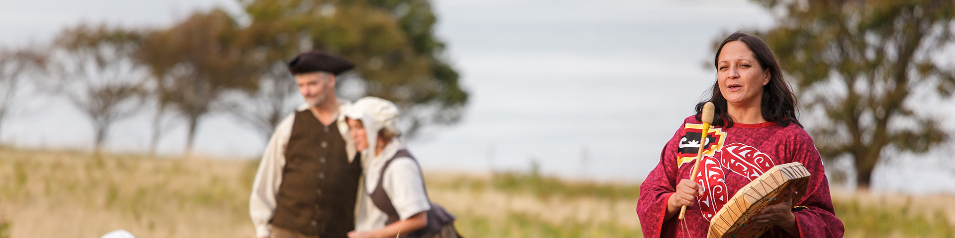 Animators dressed as Acadian settlers and a Mi'kmaq woman re-enact historical times on a hill with a view overlooking the mouth of the Hillsborough River. Skmaqn–Port-la-Joye–Fort Amherst National Historic Site.