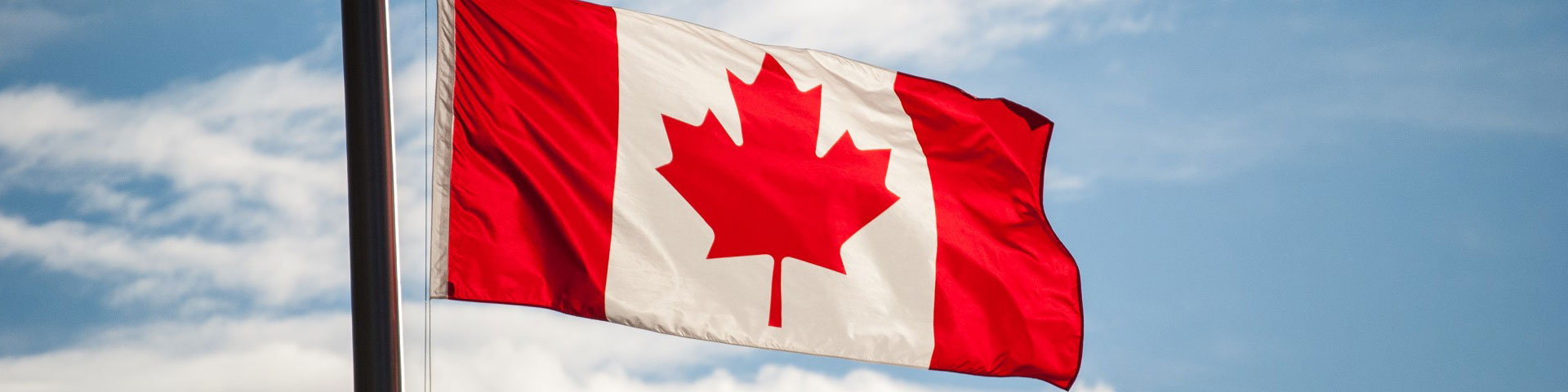 Canadian flag on a mast flying in the wind