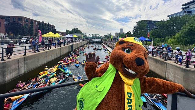 Festive atmosphere with a mascot and dozens of kayakers on the water.