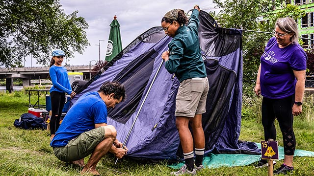 Monitrice certifiée de Parcs Canada qui aide une famille au montage d'une tente.