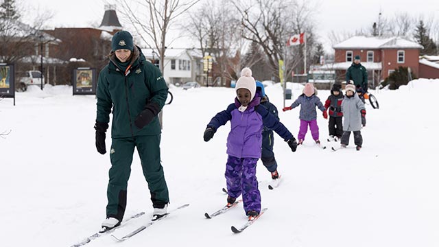 Groupe d'enfants qui apprennent le ski de fond avec un moniteur.