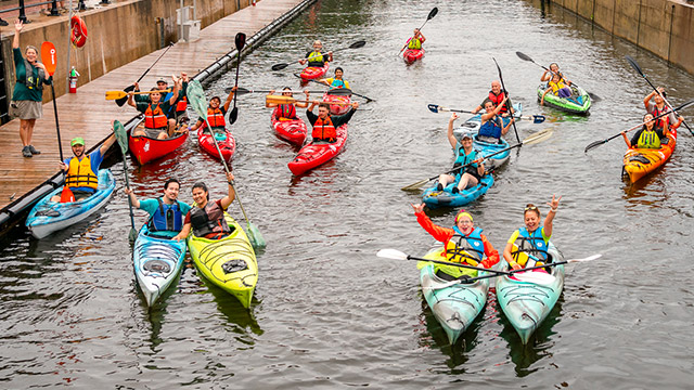 Group of happy people in their kayak on the water in a canal in summer.