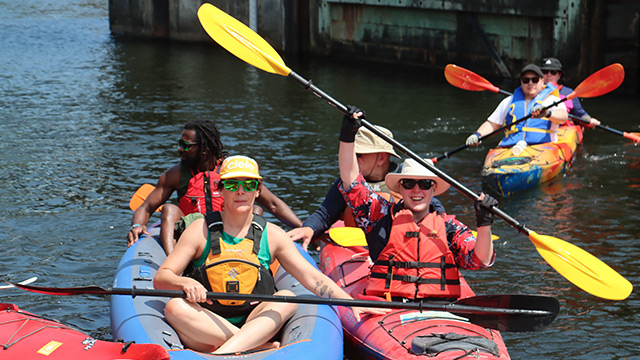 Des personnes en kayak pagaient sur un canal par une journée ensoleillée.