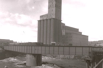 Regal Flour  - St. Lawrence Flour Mills Co. Limited. Devant on aperçoit le pont traversant l'île no 5 en amont des écluses de Saint-Gabriel. Vue vers l'ouest, côté nord du canal de Lachine. 