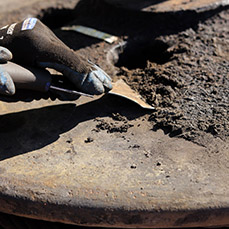 Close-up of hands holding a metal scraper on a rusty part.