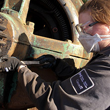Parks Canada employee cleaning a metal part with a brush
