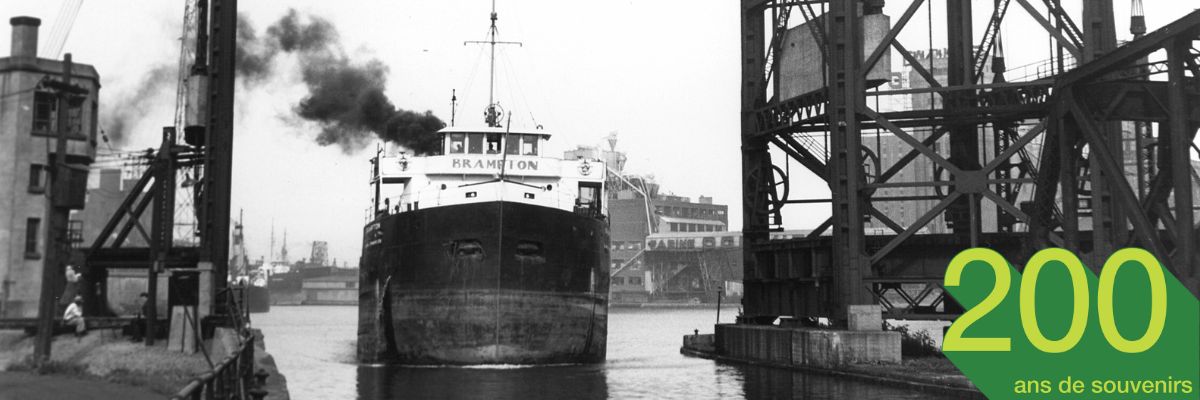 Photo noir et blanc d'un navire de marchandise navigant dans un bassin du canal de Lachine.