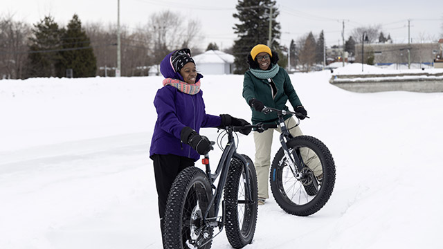 Deux femmes s'apprêtant à rouler en fat bike dans la neige.