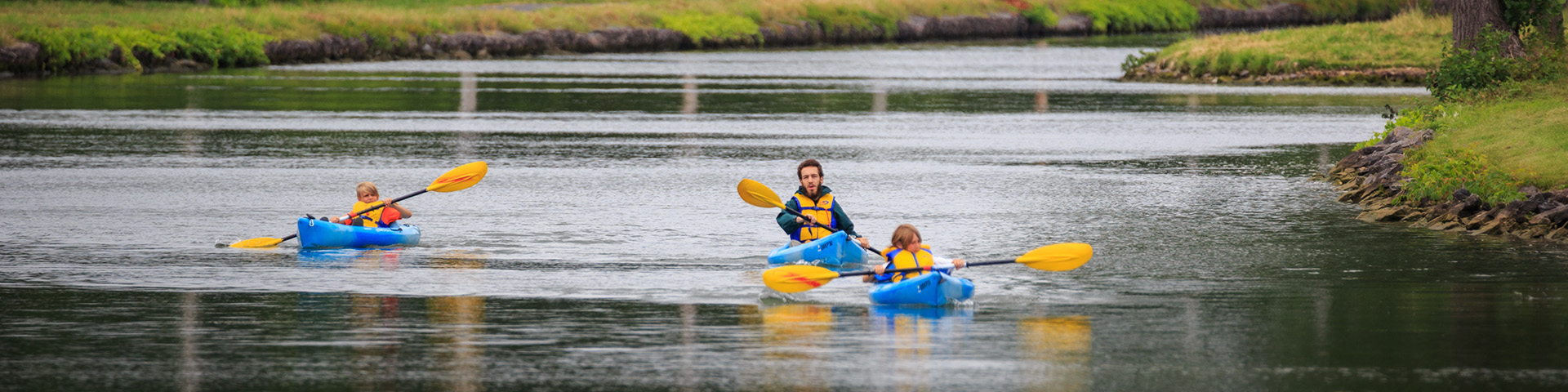 2 enfants et un employé de Parcs Canada en canot sur le canal.
