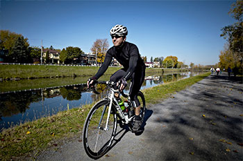 Cycliste sur un vélo blanc roulant sur une piste au bord d'un canal