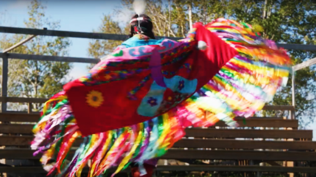 Une jeune fille autochtone danse à l'extérieur et elle est vêtue d'une régalia.