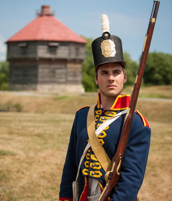 Man in Royal Artillery costume in front of the blockhouse, Coteau-du-Lac National Historic Site