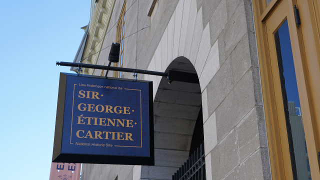 Exterior signage at Sir George-Étienne Cartier National Historic Site against a blue-sky backdrop.