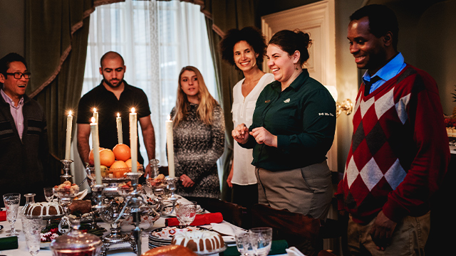 A guide from Sir George-Étienne Cartier National Historic Site leads a special “Victorian Christmas” tour with a group of adults, explaining the details of the holiday table set in the dining room of the authentic Victorian house.