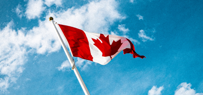 Un drapeau du Canada sur fond de ciel bleu légèrement nuageux.
