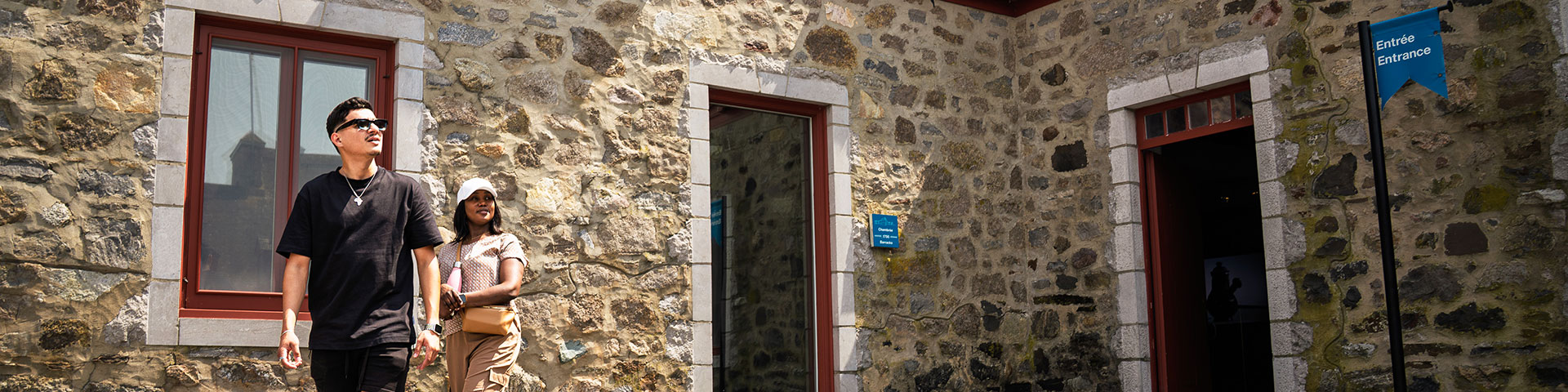 A visiting couple, a man and a woman, are standing in the open courtyard of Fort Chambly National Historic Site, looking at the stone walls.