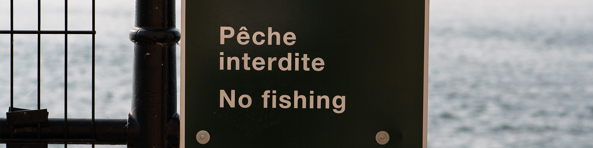 Close-up of a “no fishing” sign displayed at Fort Chambly National Historic Site, with Bassin de Chambly in the background.