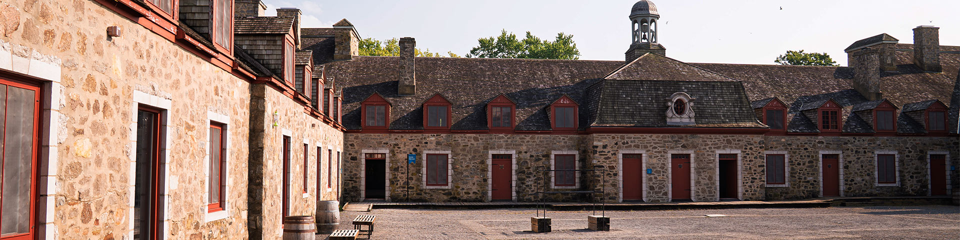 The open courtyard of Fort Chambly National Historic Site in the height of summer, with the late afternoon light in the background.