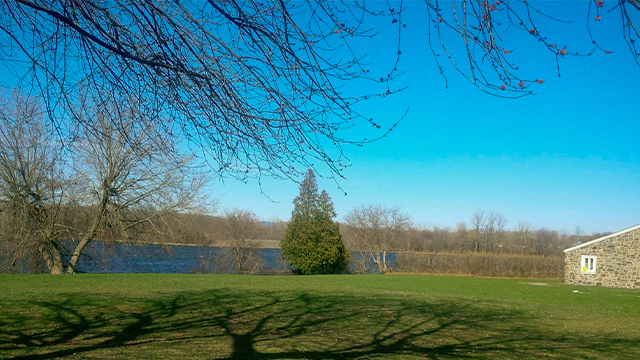 Exterior photo of the Richelieu River and part of the Fort Chambly National Historic Site guardhouse facade in spring.