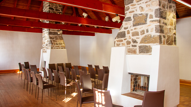 Photo inside the guardhouse at Fort Chambly National Historic Site, showing banquet chairs and a stone fireplace.