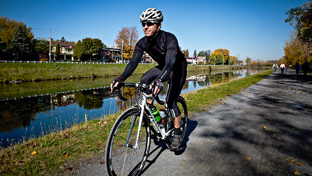 On a beautiful blue autumn day, a cyclist sets off on his road bike along the trail that runs alongside the Parks Canada historic canal connecting Chambly to Saint-Jean-sur-Richelieu.