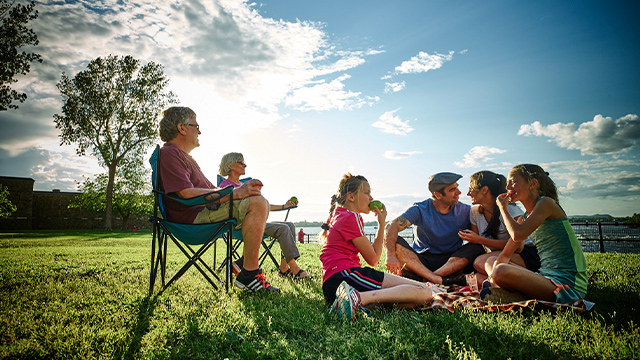 One family, including a dad, mom, grandparents, and two little girls, are enjoying a picnic on the grass at Fort Chambly National Historic Site.