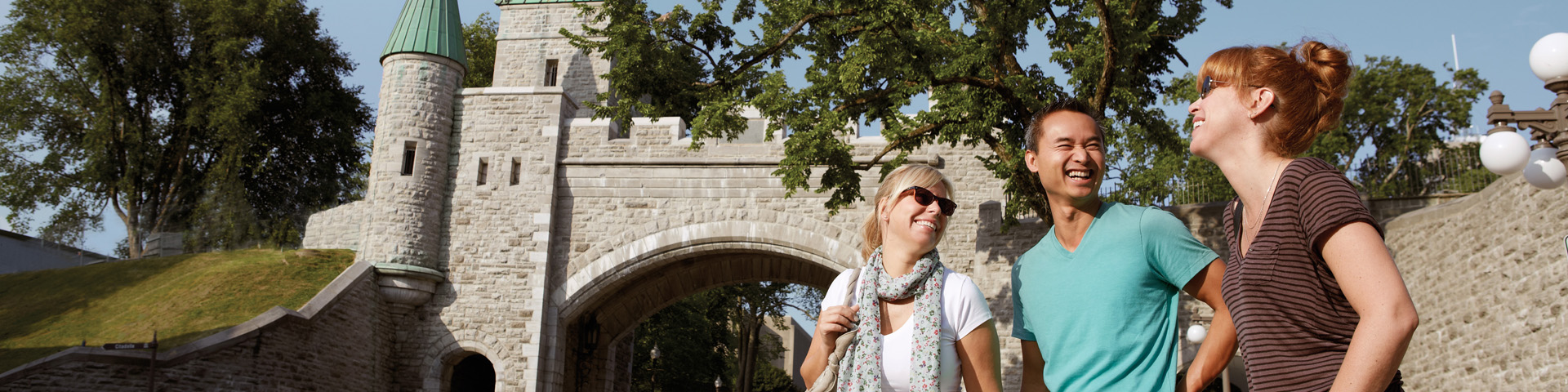 Visitors smiling in front of Saint-Louis Gate in Quebec City.