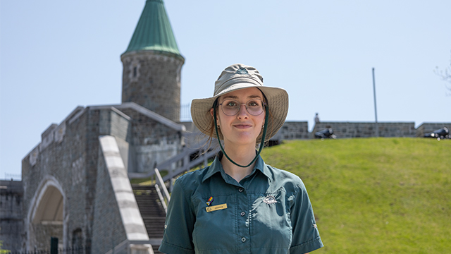 A Parks Canada employee in uniform in front of Saint-Jean Gate.