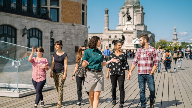 Une guide marche avec un groupe de visiteurs sur la terrasse Dufferin.