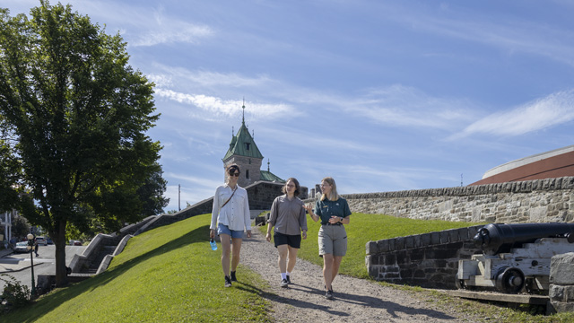 Deux visiteurs suivant la visite guidée des fortifications de Québec avec une guide de Parcs Canada.
