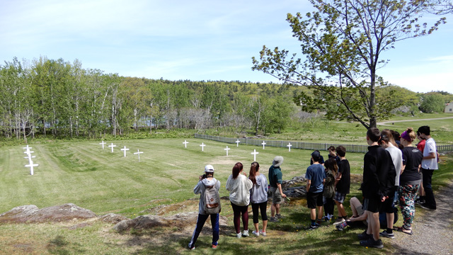 Un guide de Parcs Canada fait une visite guidée à un groupe d'élève devant le cimetière de l'ouest.