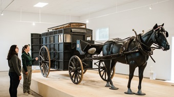 A guide introduces the horse-drawn ambulance to a visitor.