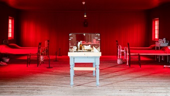 View of the red room of the lazaretto, four hospital beds from the beginning of the 20th century and a display case.