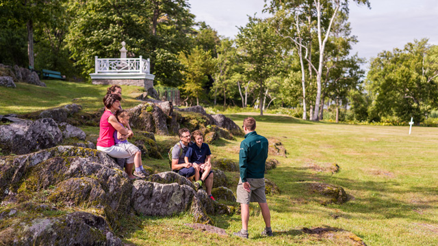 Une famille écoute un guide de Parcs Canada dans le cimetière de l'ouest.