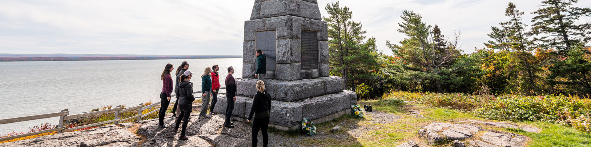 Groupe de visiteurs près de la croix celtique écoutant les explications d'un guide de Parcs Canada.