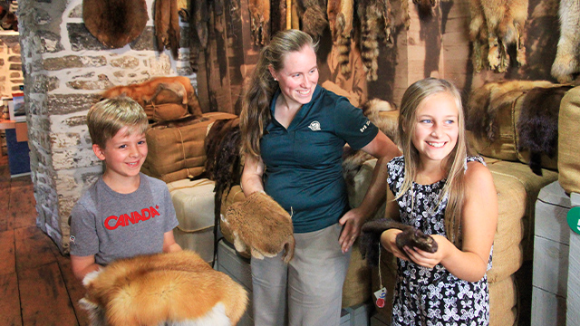 Une guide de Parcs Canada montre les différents types de fourrure à des enfants de camp de jour en visite au lieu historique national du Commerce-de-la-Fourrure-à-Lachine.