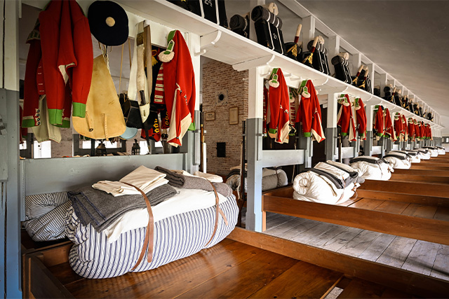 Beds and uniforms of the soldiers who stayed in the barrack room at Fort Lennox National Historic Site.