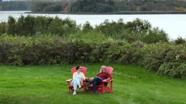 Un couple se prélasse dans les chaises rouges du lieu historique national du Fort-Lennox.