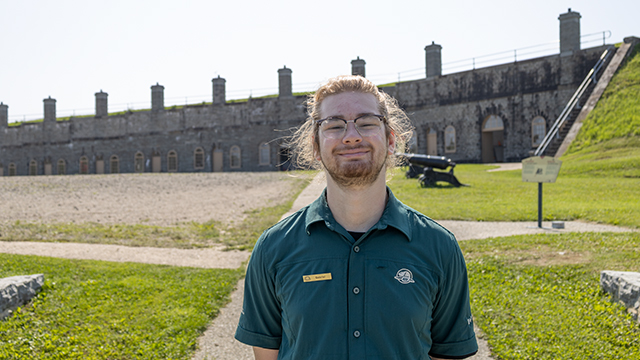 A uniformed Parks Canada employee poses in front of the casemates at Fort No.1.