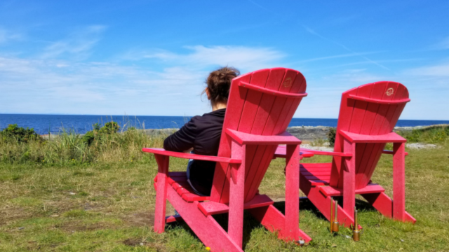 Une femme assise dans une chaise rouge admise le fleuve. 