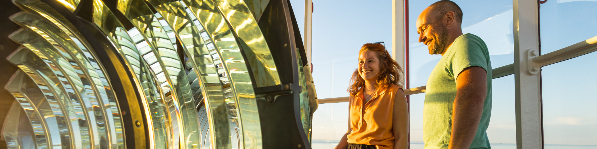 Two visitors are looking at a beacon at the top of a lighthouse.