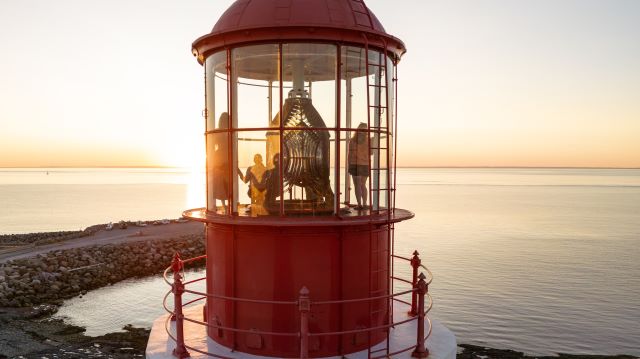 A group of people look out over the river from the top of a lighthouse.
