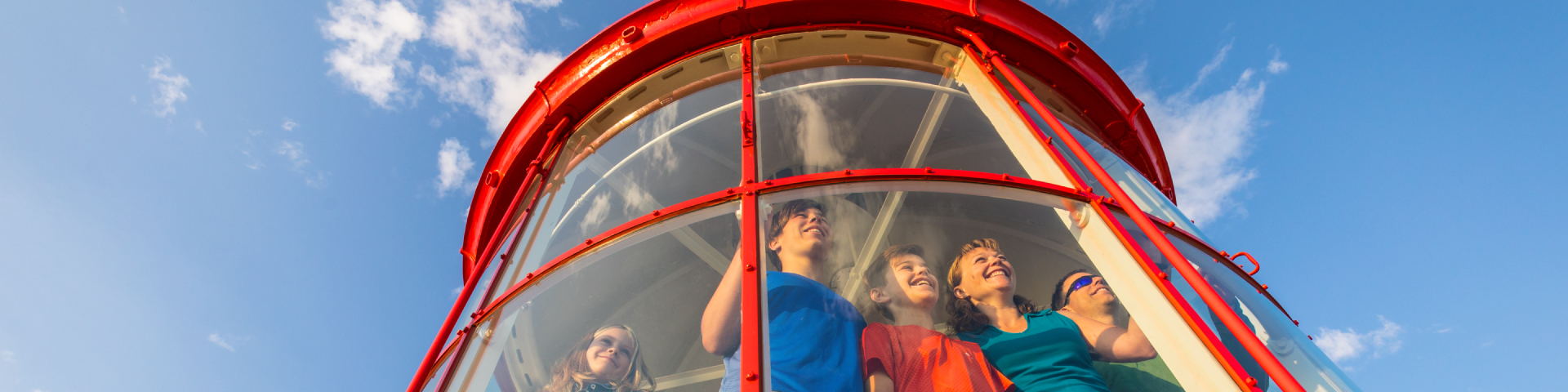 A family in the lantern room of a lighthouse is looking further away. 