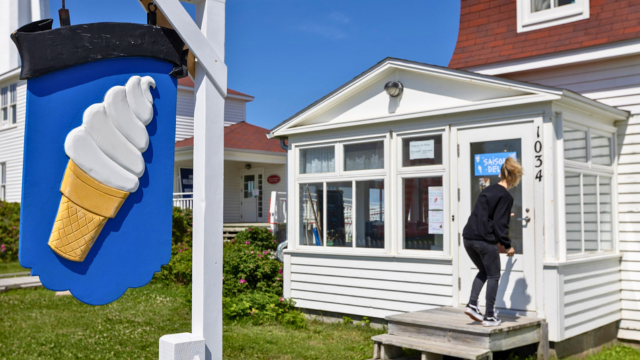 A visitor walks past a sign showing a ice cream cone and enters an old building.