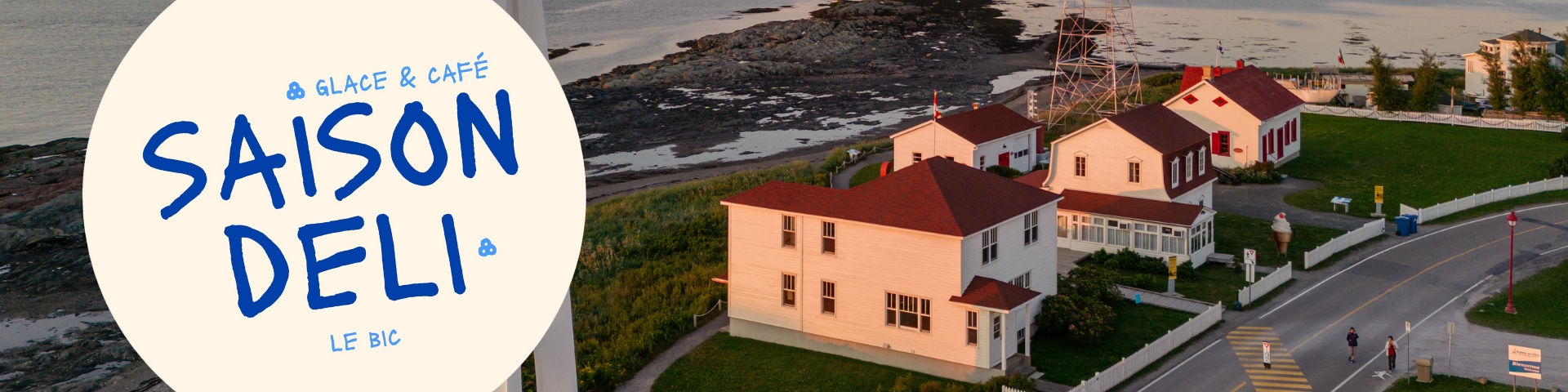 Bâtiments blanc et rouge d'une station de phare avec, à gauche, le logo de Saison Deli. 