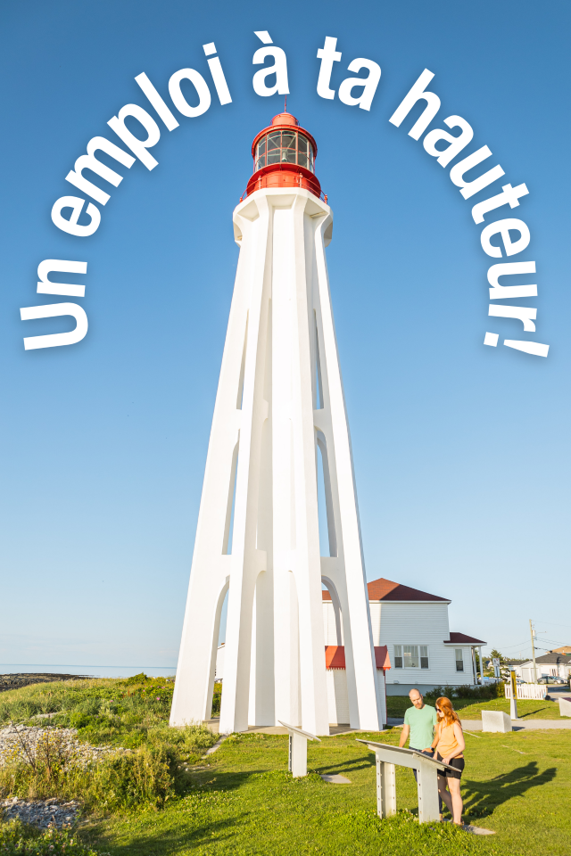 Deux visiteurs lisent un panneau d'interprétation au pied d'un phare. 