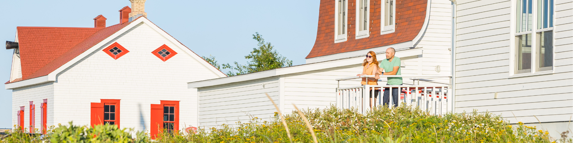 Two visitors standing on a heritage building patio are looking at the see. 