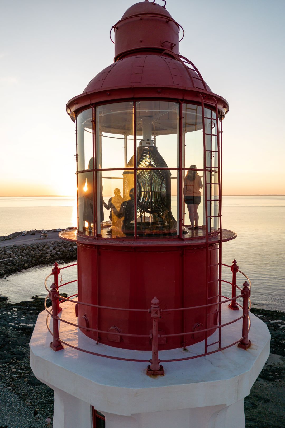 A family watches the sunset from the dome of a lighthouse.