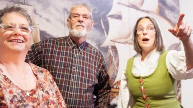 Two visitors and an interpreter express their surprise at seeing an item in a museum exhibition. 
